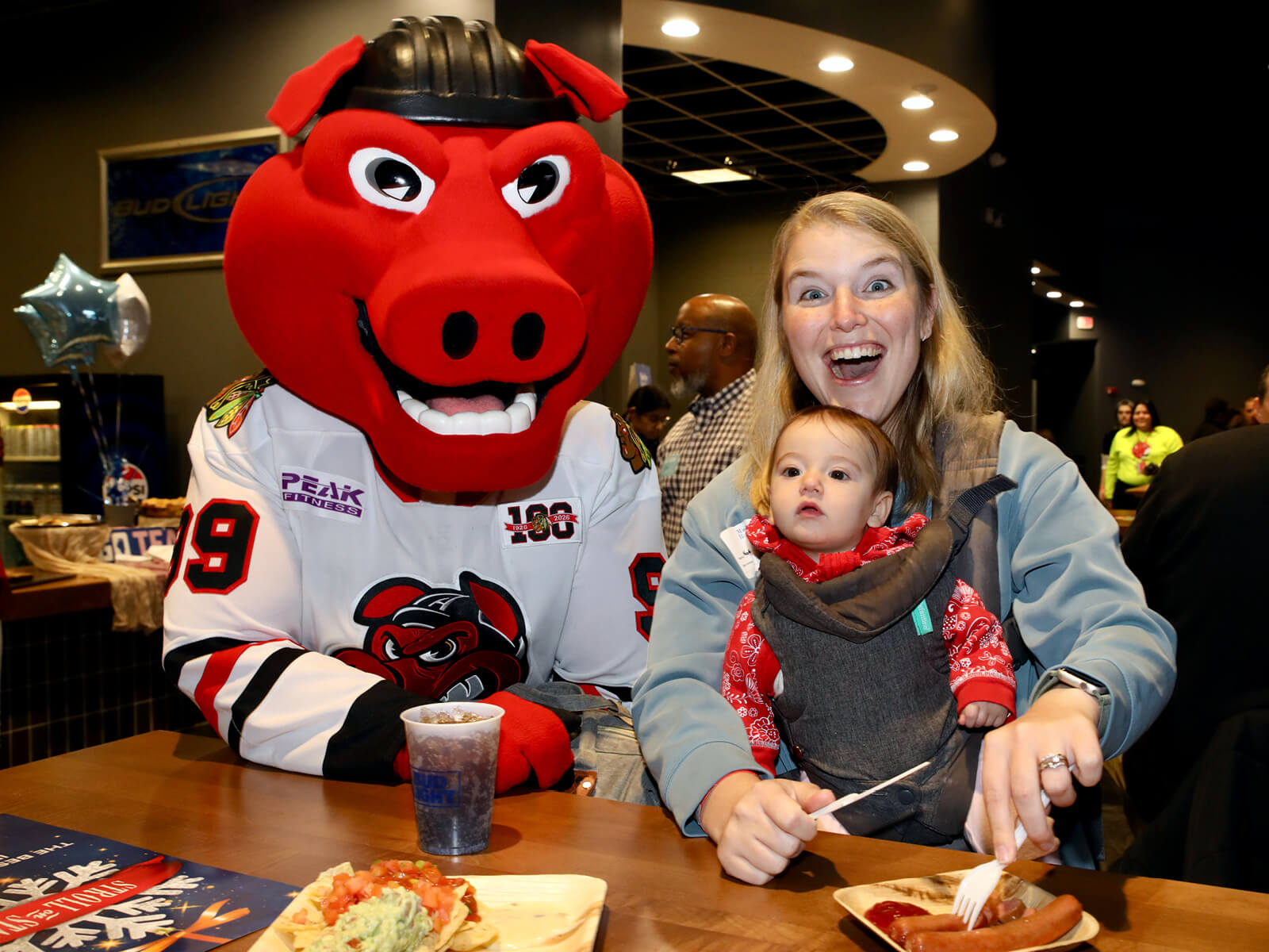 A mother and baby posing with Rockford IceHogs mascot Hammy
