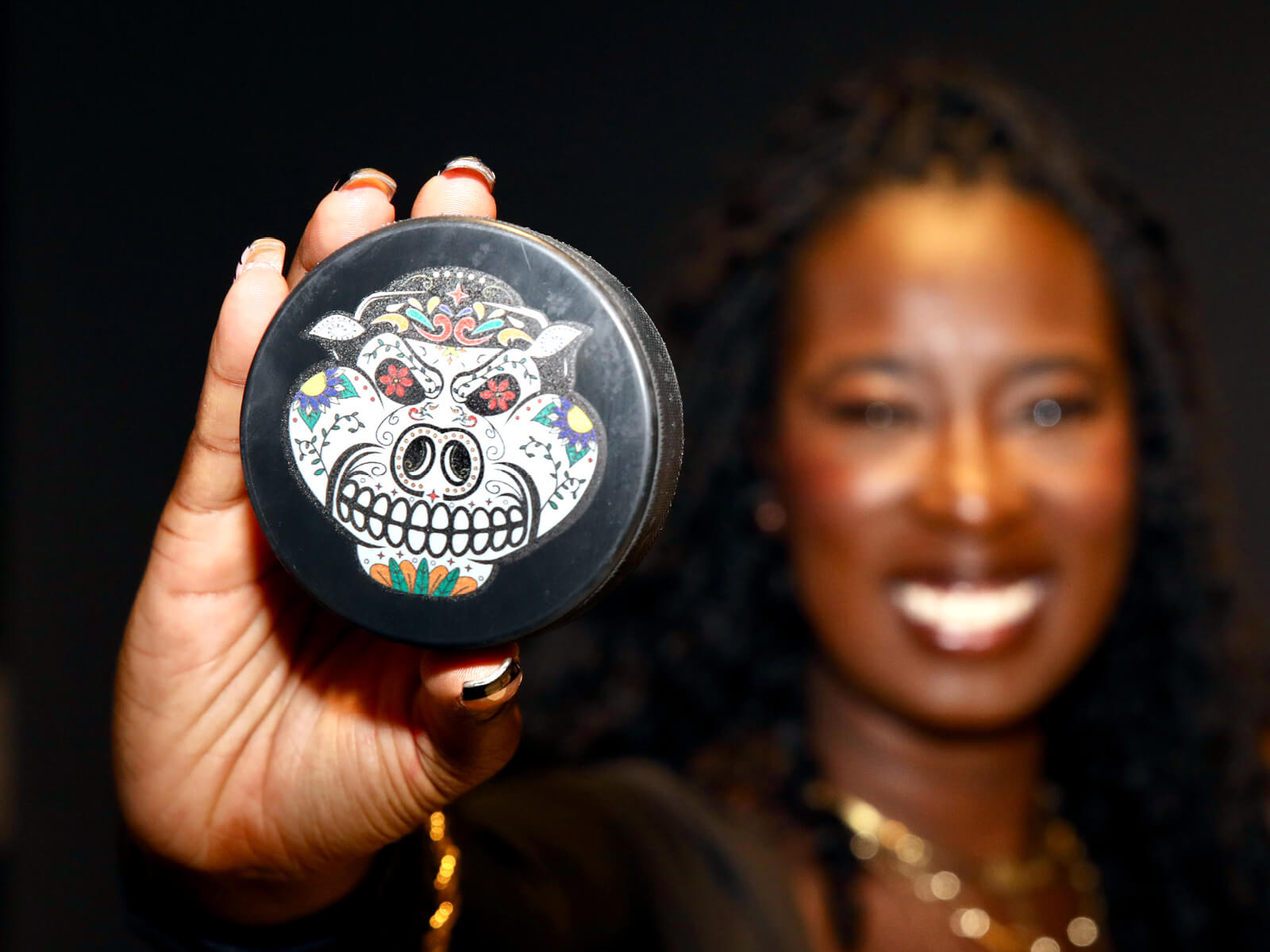 A woman holding an IceHogs Day of the Dead puck