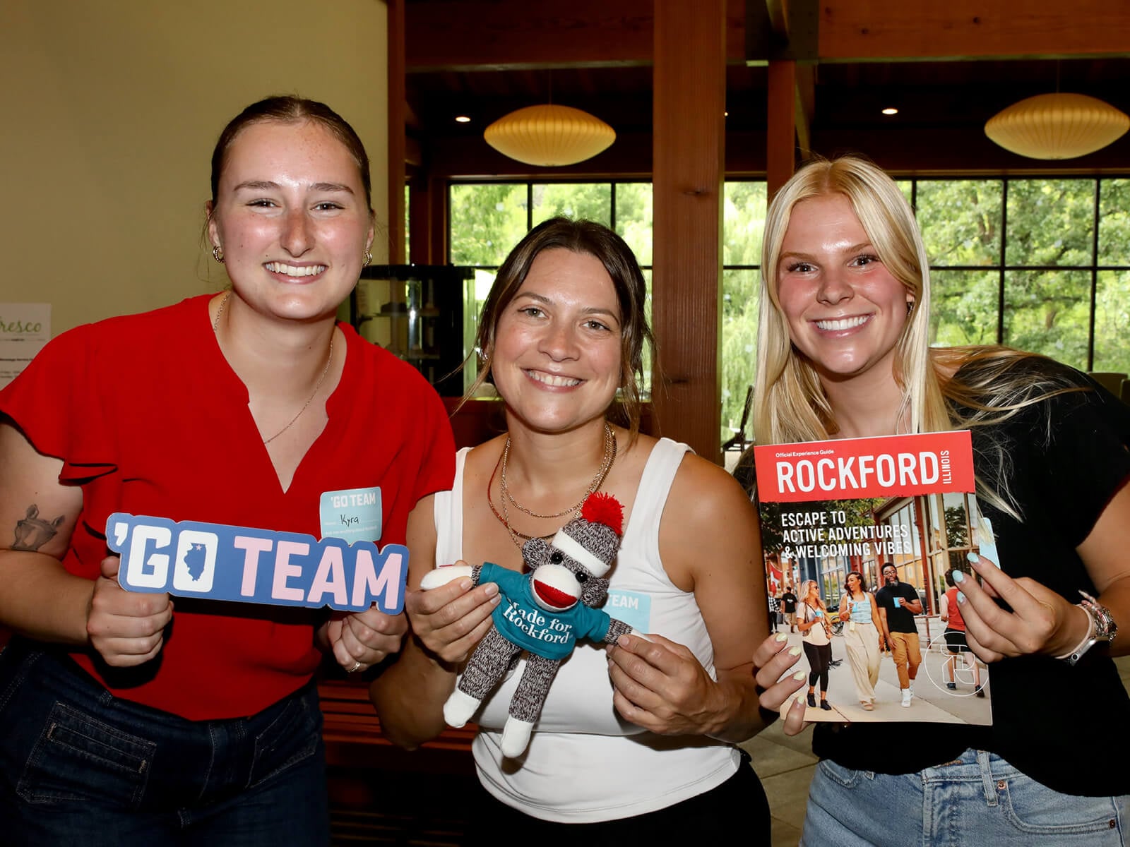 Rockford residents posing with a sock monkey and Move to Rockford Guide