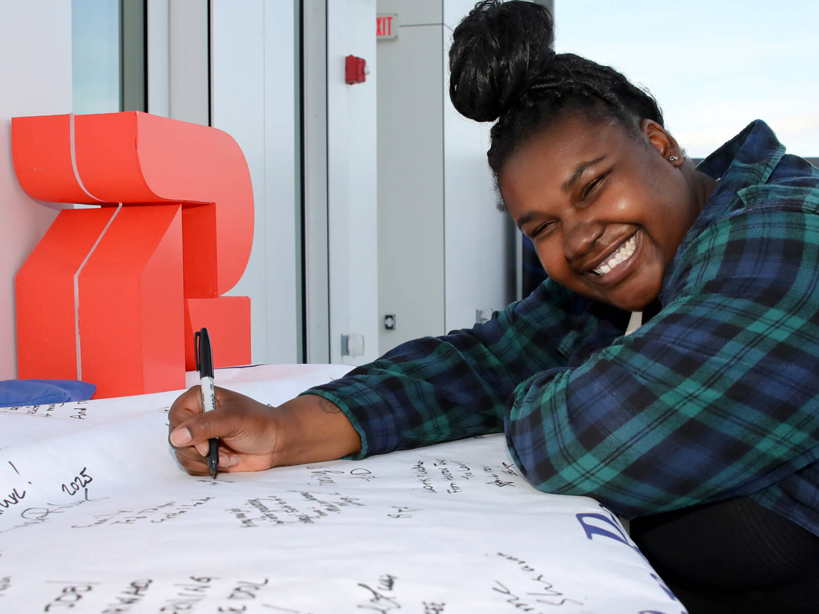 A woman signing a banner at a Rockford new resident mixer