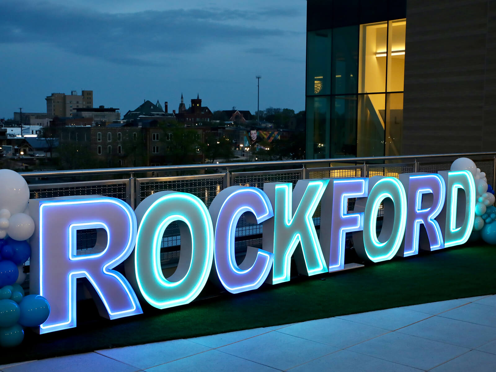 A Rockford sign glowing on the Rockford Public Library Terrace
