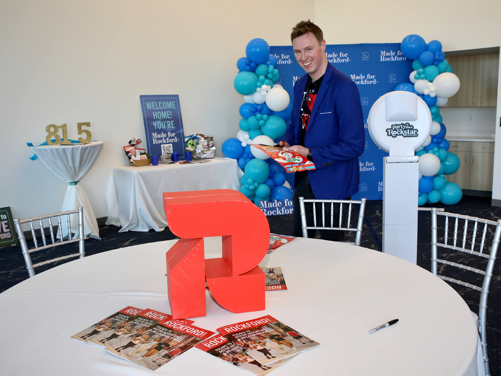 A man walking past a table with a GoRockford logo centerpiece at a new resident mixer