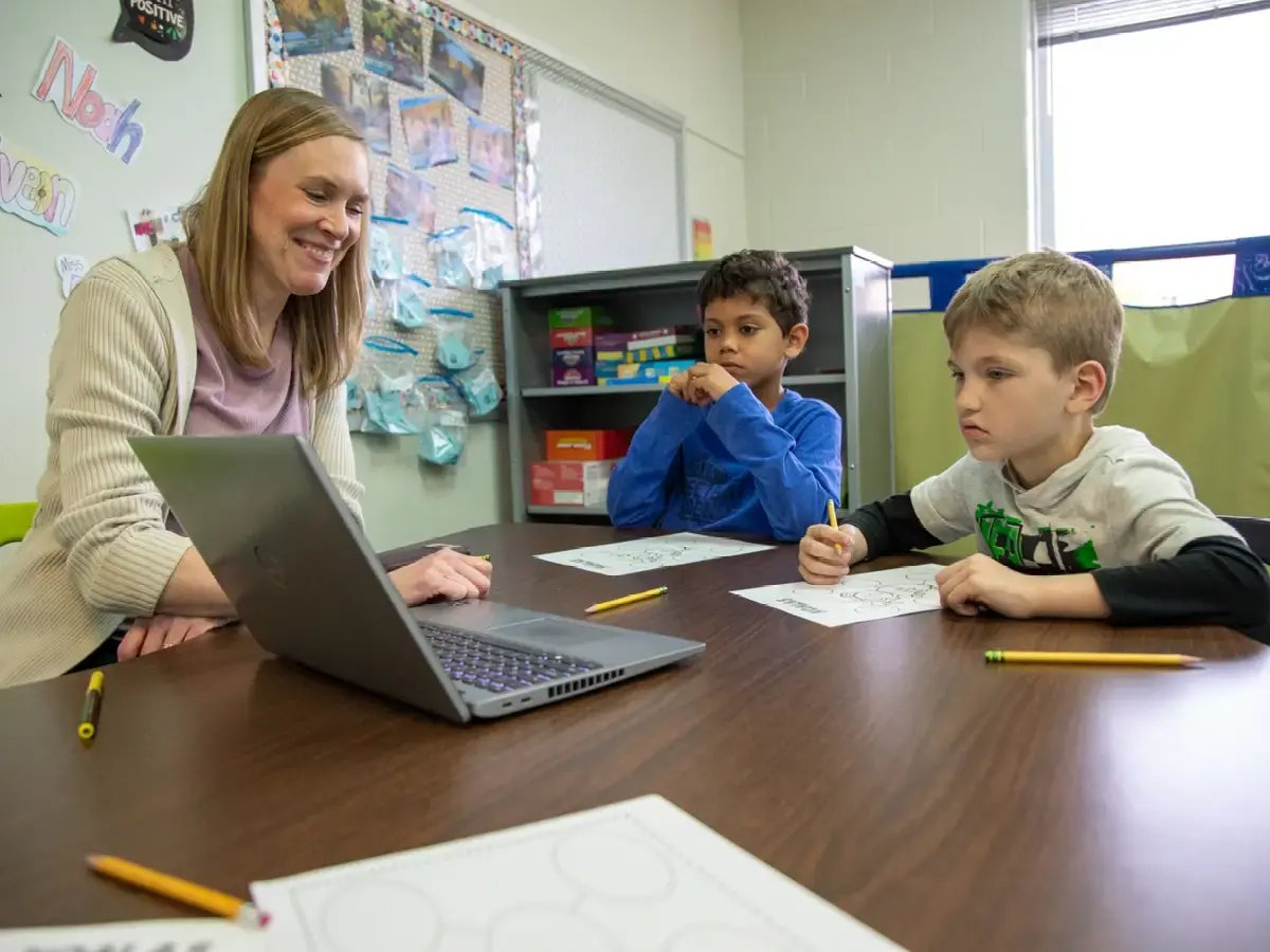 Teacher with two of her students at a table.