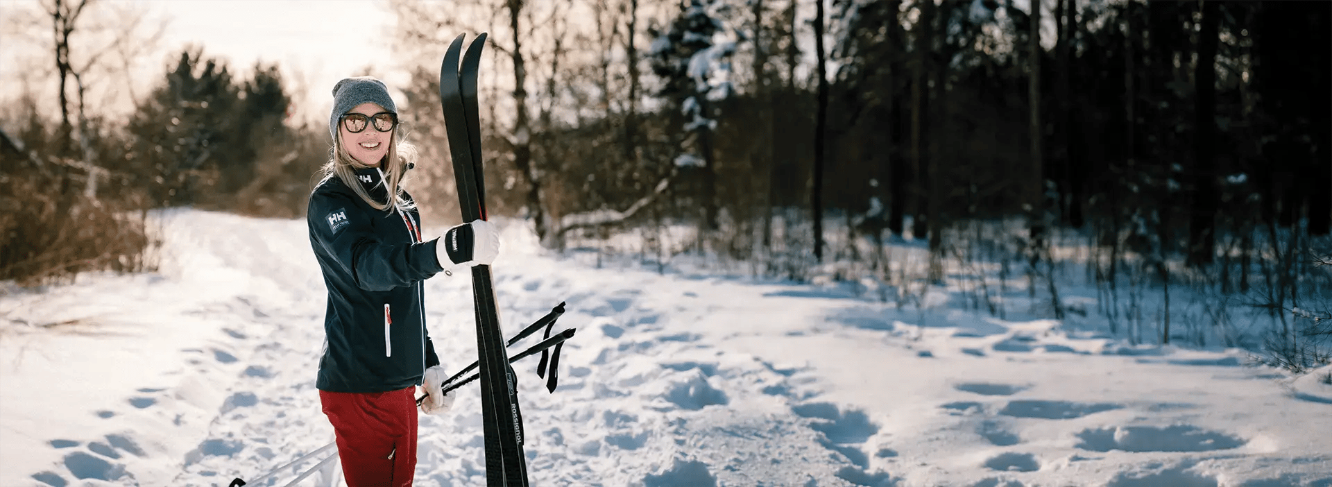 Woman holding skis on a trail covered in snow.