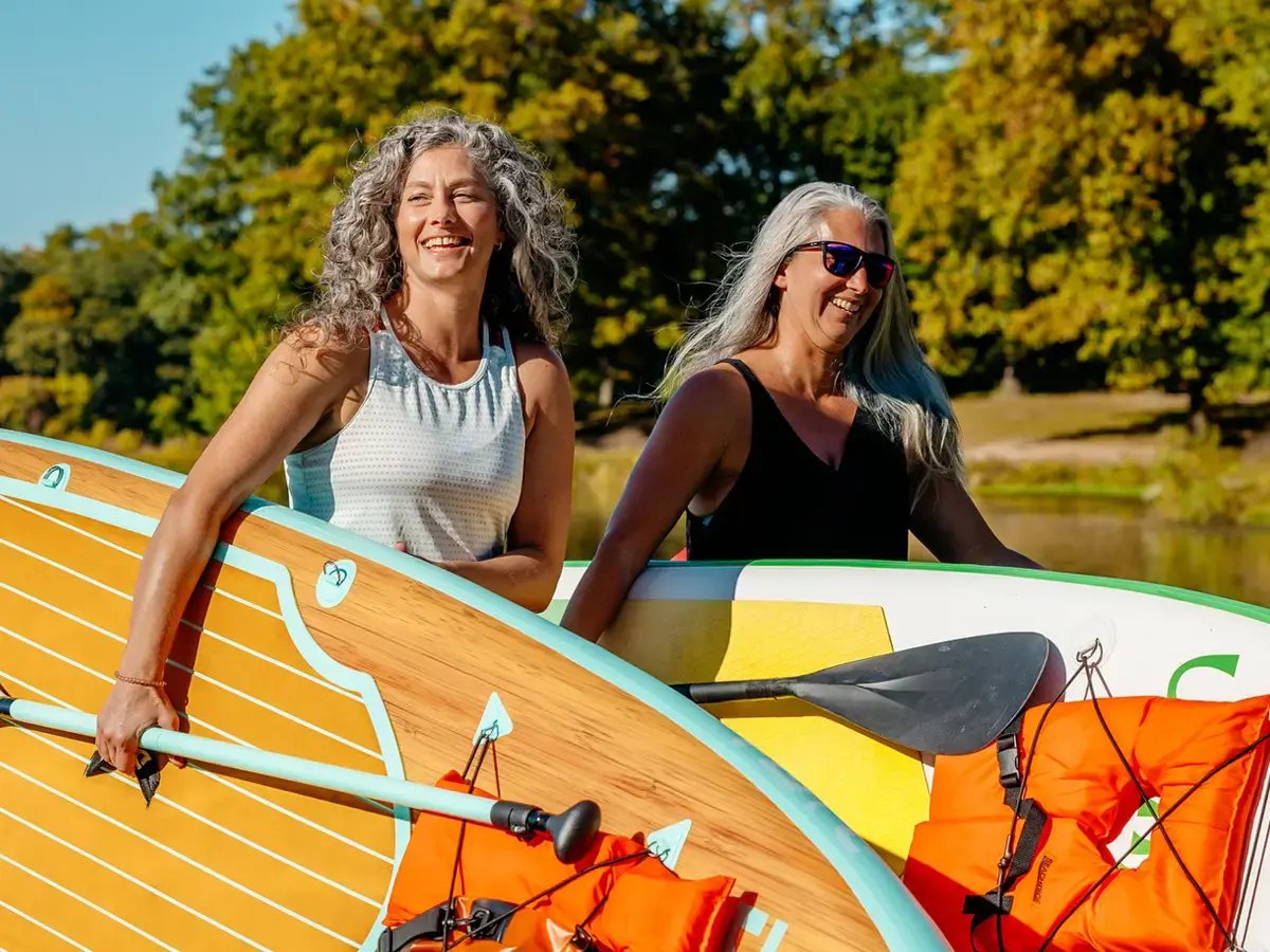 Friends carrying paddleboards next to the Rock River